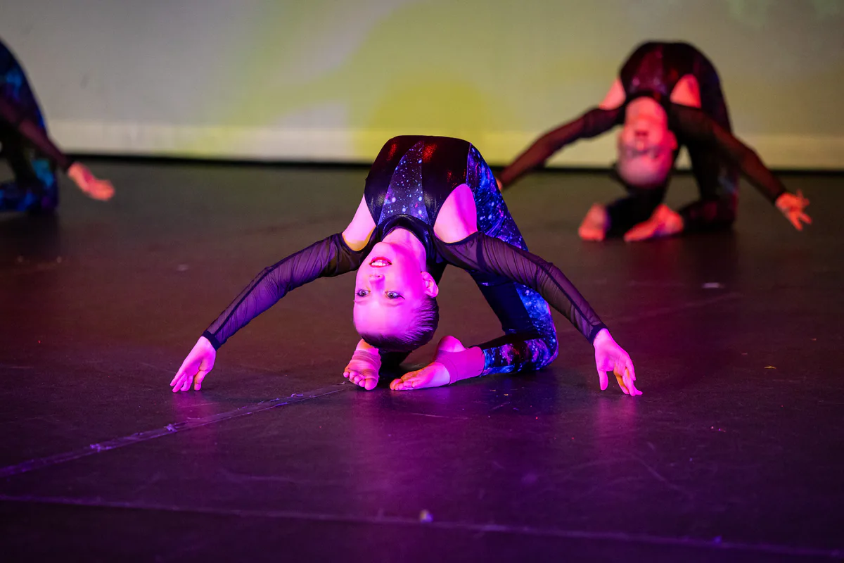 Acro dancer performing a controlled back bend on stage with JL Dance Academy in Ripley